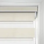 Modern beige roller blinds in a white window frame.