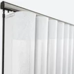 Close-up of white textured vertical blinds on rail.