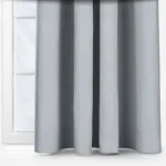 Grey curtains in front of a window in a white room.