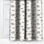Eye patterned curtains hanging beside window.