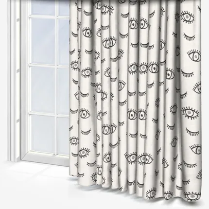 Eye-patterned curtains beside a window in a bright room.