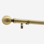 Brass curtain rod with spherical finial on white background.