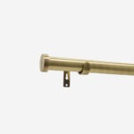 Brass curtain rod with wall bracket on white background.
