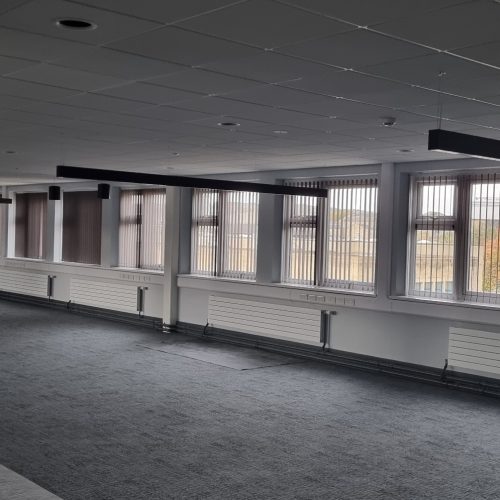 Empty office space with large windows and grey carpet