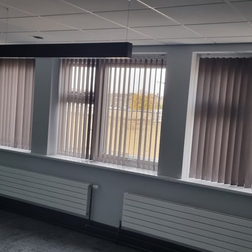 Empty office with green wall and vertical blinds.