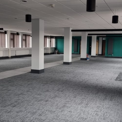 Spacious, empty office with grey carpet and columns.