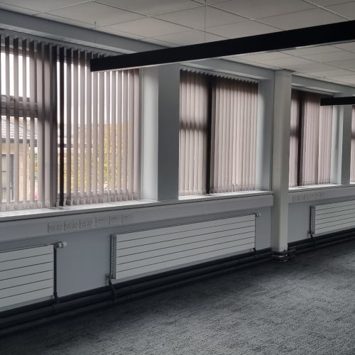 Modern office with rows of vertical blinds and windows.