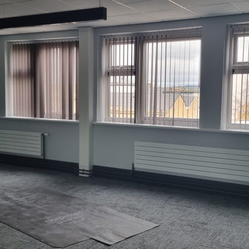 Empty office room with multiple windows and city view.