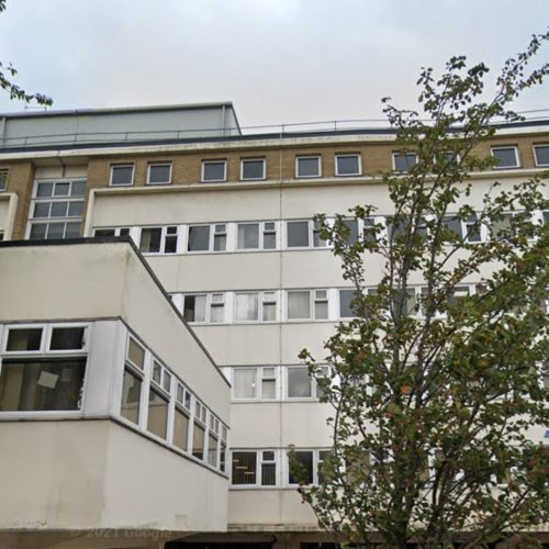 Urban building exterior with parked cars and trees